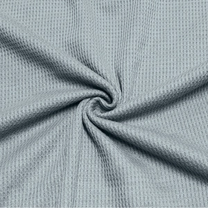 Macro detail of breathable waffle knit fabric texture on light blue men's Henley shirt