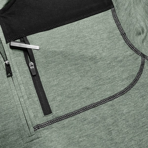 Detail of green heather knit fabric with black reinforced stitching and zipper pocket