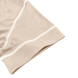 Macro detail of khaki knit fabric showing white contrast double stitching on the cuff
