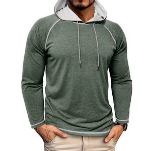 Dettaglio felpa con cappuccio verde scuro con cuciture bianche a contrasto e maniche raglan
