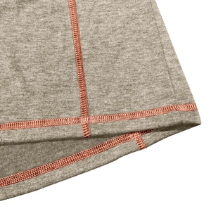 Macro detail of men's thermal Henley shirt with orange contrast stitching on gray fabric