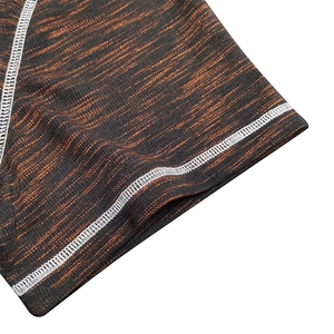 Detailed view of the flatlock stitching on black and orange textured knit fabric shirts