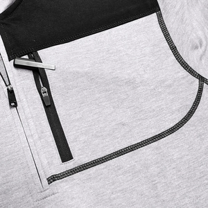 Detail showing grey knit texture with black paneling and metallic zipper on tactical jacket