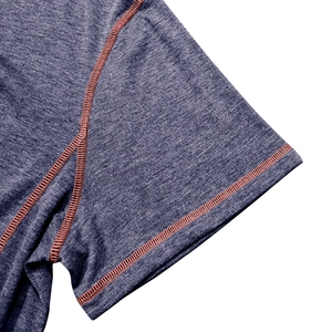 Macro shot of dark grey-blue athletic fabric with orange contrast flatlock stitching details