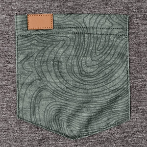 Détail de la poche poitrine vert forêt avec imprimé contour et étiquette cuir sur gilet gris