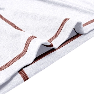 Detail of white long sleeve polo shirt with brown contrast stitching and knit texture