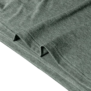 Detailed close-up showing fine knit texture and double-needle hem of the green polo shirt