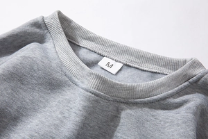 Close-up of the ribbed crewneck and soft knit texture of this light grey oversize sweatshirt