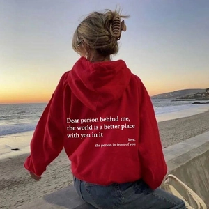 Rückansicht roter Oversize-Hoodie mit inspirierendem Text vor Strandhintergrund
