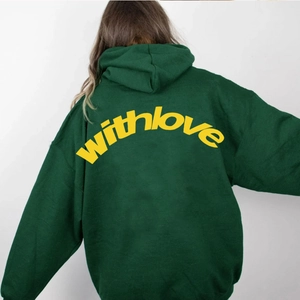 Detail eines übergroßen dunkelgrünen Hoodies mit gelbem withlove Text auf dem Rücken