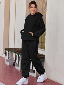 Detail of a women's black oversized hooded tracksuit set featuring soft knitted fabric