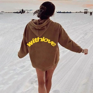 Außenaufnahme der Rückseite eines braunen Oversized-Hoodies mit gelbem Textaufdruck