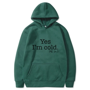 Detail of a dark green hoodie featuring kangaroo pocket and Yes I'm Cold printed text