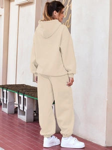 Detail view of beige two-piece hooded tracksuit showing drop shoulder fit and joggers