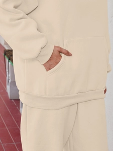 Detail view of beige hoodie with front kangaroo pocket and ribbed cuffs in casual style