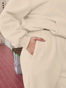 Detailed close-up of beige knit hoodie pocket and soft ribbed cuffs on lounge set