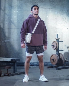 Deep gray camo dual-layer running shorts with purple hoodie in industrial gym setting