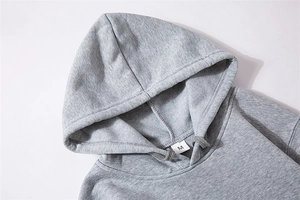 Close-up of light grey hoodie neckline showing fabric texture and stitched size label