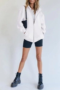 Close-up of white oversized zip-up hoodie featuring silver metal zipper and drawstring