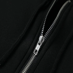 Close-up detail of smooth silver metal zipper on black heavy knit fabric hoodie