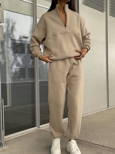Detail view of beige two-piece tracksuit with half-zip collar and ribbed jogger cuffs