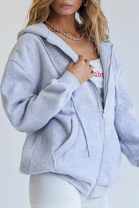 Close-up of light grey oversized zip-up hoodie with drawstring hood and front pockets