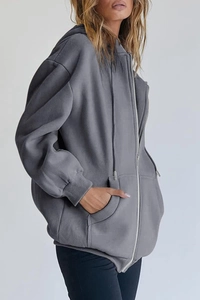Close-up side view of an oversized dark grey hoodie with drawstring hood and zipper detail