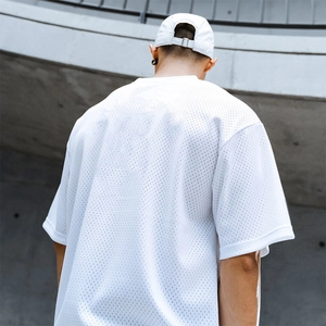 Rear view of man in white mesh oversized fitness t-shirt against a concrete wall