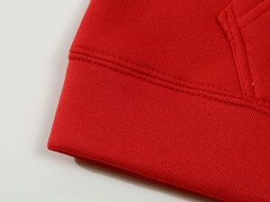 Close-up of red hoodie showing rib-knit hem and high-density stitching details