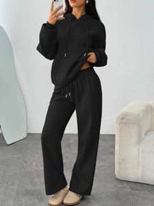 Detail view of black hoodie and wide-leg sweatpants set with drawstring and kangaroo pocket