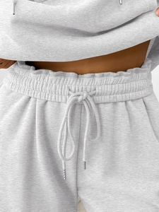 Detail of high-waisted grey sweatpants with elastic drawstring and metal tips