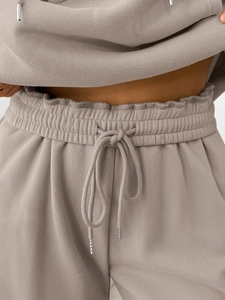 Detail of taupe tracksuit joggers with elastic drawstring waist and ruffle trim edges