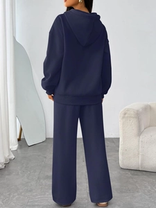 Detail of navy blue oversized hoodie and matching wide-leg pants on a standing model
