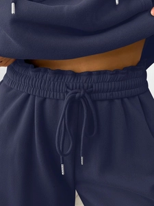 Macro detail of navy blue tracksuit showing elastic waist with silver metal drawstring tips