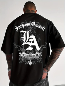 Close-up of Gothic Surpass Oneself text and LA print on black heavy cotton street T-shirt