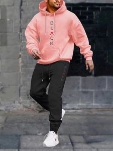 Dettaglio felpa con cappuccio rosa e joggers neri con scritte verticali sul petto