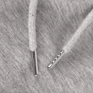 Macro view of grey adjustable drawstring with decorative silver metal tips on trousers