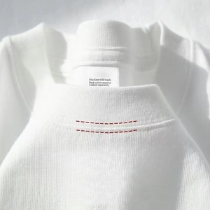 Primer plano del cuello redondo de camiseta blanca con detalle de doble costura reforzada