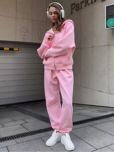 Dettaglio della tuta sportiva rosa con felpa con cappuccio e pantaloni abbinati su modella