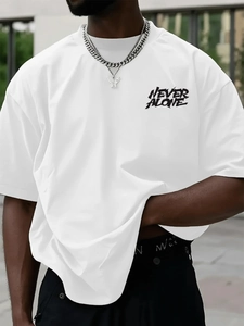Detail of the NEVER ALONE black letter print on a loose white oversized cotton T-shirt
