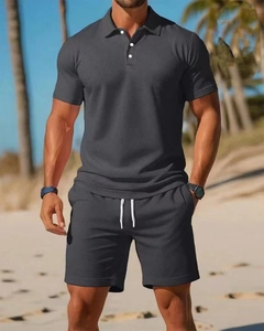 Close-up of men's dark grey piqué polo set with breathable mesh texture and beach backdrop