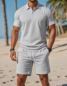 Detail shot of light grey knit Polo shirt and matching drawstring shorts on a beach
