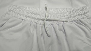 Detail view of white athletic shorts with elastic waistband and mesh breathable fabric