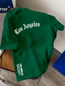 Detail eines locker sitzenden grünen Baumwoll-T-Shirts mit weißem Los Angeles Buchstaben-Aufdruck