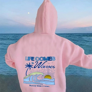 Détail du sweat à capuche rose clair avec imprimé graphique de vagues et palmiers