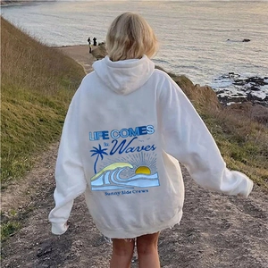 Détail d'un sweat à capuche blanc oversize avec imprimé vagues et palmier bleu au dos