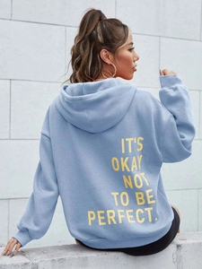 Detailansicht des gelben Slogan-Aufdrucks auf der Rückseite des hellblauen Oversize-Hoodies