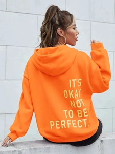 Nahaufnahme des orangefarbenen Kapuzenpullovers mit gelbem Slogan-Print auf der Rückseite