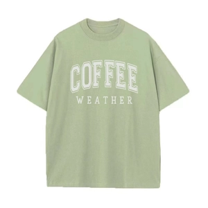 Detail van de COFFEE WEATHER print op een saliegroen oversized katoenen t-shirt