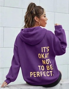 Detail eines lila Kapuzenpullovers mit gelbem Slogan und weichen Rippbündchen